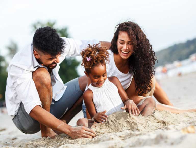 Parents building a sandcastle with daughter on beach